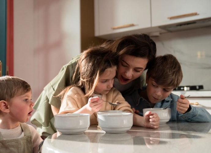 Mother and children enjoying a cozy breakfast together in a modern kitchen setting.