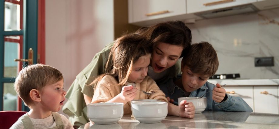 Mother and children enjoying a cozy breakfast together in a modern kitchen setting.