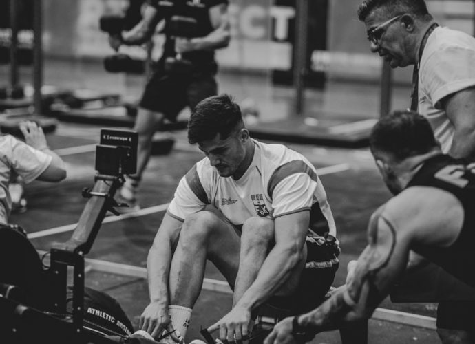Men engaged in a competitive gym rowing session, highlighting teamwork and fitness.